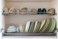 Clean dishes in white and green tones in a drying cabinet. Cups, glasses, mugs, plates, bowls, saucers on metal shelves. Concept Royalty Free Stock Photo