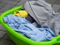 Clean dried clothes laying in a green laundry basket outdoors