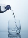 Clean drinking water flows from the bottle into a clear glass with beautiful bubbles Royalty Free Stock Photo