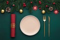 Clean empty plate, golden cutlery. Festive table setting with christmas decorations. Celebration xmas eve, flat lay. Red, gold and Royalty Free Stock Photo