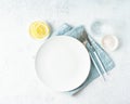 Clean empty white plate, glass of water, fork and knife on white stone table, copy space, mock up Royalty Free Stock Photo