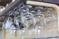 Clean empty wine glasses in row hang on shelf bar in light sunshine Royalty Free Stock Photo