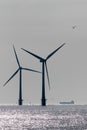 Clean energy production development. Offshore wind power turbine silhouette with supply vessel