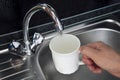 Clean filtered water flows from the tap. Danger of untreated drinking water. filling water in white porcelain glass at Royalty Free Stock Photo