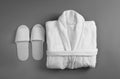 Clean folded bathrobe and slippers on grey background Royalty Free Stock Photo
