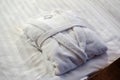 Clean folded bathrobe on white bed. Royalty Free Stock Photo