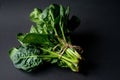 Clean food concept. Bunch of leaves of fresh organic spinach greens on a black background. Healthy detox spring-summer diet. Vegan Royalty Free Stock Photo