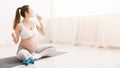 Young pregnant woman drinking water sitting in lotus position Royalty Free Stock Photo