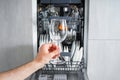 Dishwasher, open and loaded with dishes, front view. Man hand taking out clean wine glass, after washing Royalty Free Stock Photo