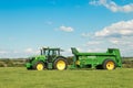 A green John Deere tractors pulling bunning muck spreaders