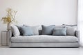 a clean, grey sofa with one bright cushion against a white wall