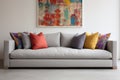 a clean, grey sofa with one bright cushion against a white wall