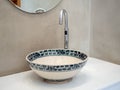 Clean loft style bathroom interior with porcelain sink basin faucet on white marble shelf and round mirror on concrete wall Royalty Free Stock Photo