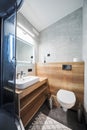 Clean, minimalist grey bathroom with ceramic sink and illuminated mirror indoors.