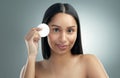 Clean, moisturise, repeat. a beautiful young woman holding a cotton pad against her face.