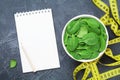 Clean notebook, green spinach leaves and tape measure top view. Diet and healthy food concept. Royalty Free Stock Photo