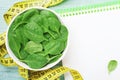 Clean notebook, green spinach leaves and tape measure on wooden table from above. Diet and healthy food concept. Royalty Free Stock Photo