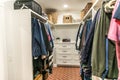 A clean and organized closet with some hanging clothes and shelves Royalty Free Stock Photo