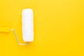 Clean paint roller with yellow handle on the yellow background with copy space