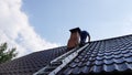 a man climbs a metal ladder to the roof of the bathhouse to clean the pipe from soot and soot Royalty Free Stock Photo