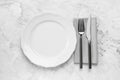 Clean plate and shiny silver cutlery on white marble table, flat lay Royalty Free Stock Photo
