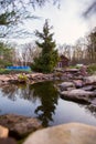 Clean pond in the garden of a country house. Stones and spruce on the lake. Quiet evening. The water reflects the sky