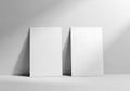 Two blank rectangular cards leaning against a light gray wall with subtle shadow patterns Royalty Free Stock Photo