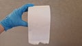 Roll of toilet paper in a hand wearing surgical rubber glove