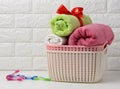 Clean rolled terry towels in a plastic basket on a white shelf, bathroom interior