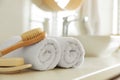 Clean rolled towels, brush and bar of soap on countertop in bathroom