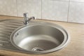 Clean round metal kitchen sink with faucet and water drops from leak