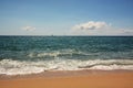 Clean sandy beach, azure Mediterranean sea, sailboat on the horizon