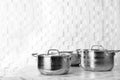 Clean saucepans and colander on table against white wall Royalty Free Stock Photo