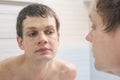 A clean-shaven young man looks in mirror Royalty Free Stock Photo