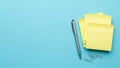 A stack of yellow sticky notes with a silver pen and paper clips on a blue desk. Royalty Free Stock Photo