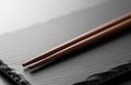 A clean single pair of chopsticks placed neatly on slate with soft light and high visual balance in still composition Royalty Free Stock Photo