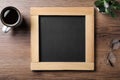 Clean small blackboard, coffee, chalk and glasses on wooden table, flat lay Royalty Free Stock Photo