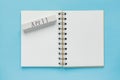 Clean spiral note book for notes and messages and april wooden calendar bar on blue background. Minimal business flat lay