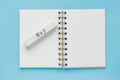 Clean spiral note book for notes and messages and may wooden calendar bar on blue background. Minimal business flat lay