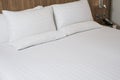 Clean towel on bed in modern hotel bedroom. White bed sheets and pillows. White bathrobe on the hotel bed Royalty Free Stock Photo