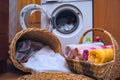 Clean Towels, Dirty Linen in Wicker Laundry Baskets, Liquid Detergents on the Floor Near the Front Load Washing Machine with Royalty Free Stock Photo