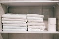 Clean towels on shelf in bathroom. White towels on the shelf. Toilet paper rolls in the closet Royalty Free Stock Photo