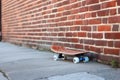 clean, untouched skateboard resting on brick wall