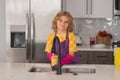 Clean washed dishes, dishwashing liquid with foam. Child helper housekeeping. Little boy sweeping and cleaning dishes at