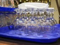 Clean, washed, glass transparent mugs for beer and wine glasses for wine, stand in groups on plastic blue trays, on  wooden bar Royalty Free Stock Photo