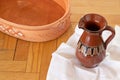 Clean water in ancient jar, clay basin, and white linen cloth on wooden floor Royalty Free Stock Photo