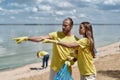 Clean water. Two young eco activists, man and woman holding trash bag and discussing something while cleaning beach area Royalty Free Stock Photo