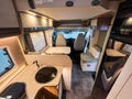Clean, well-lit interior of a modern camper van, featuring a compact kitchenette, a small table, and the driver and passenger Royalty Free Stock Photo