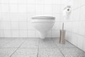 Clean white bathroom with toilet paper and toilet brush with withe tiles and a floating toilet Royalty Free Stock Photo