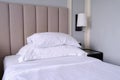 Clean white bed in the bedroom. Bed with white linens, bedside table and wall sconce Royalty Free Stock Photo